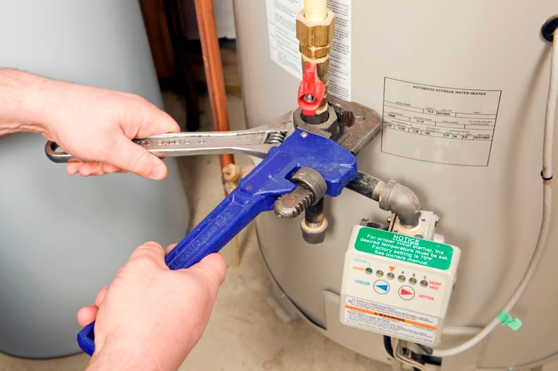 Plumber repairing water heater pipe connection in Atlanta, Georgia home