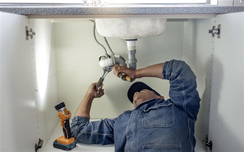 Plumber repairing kitchen sink drain pipes in Atlanta, Georgia