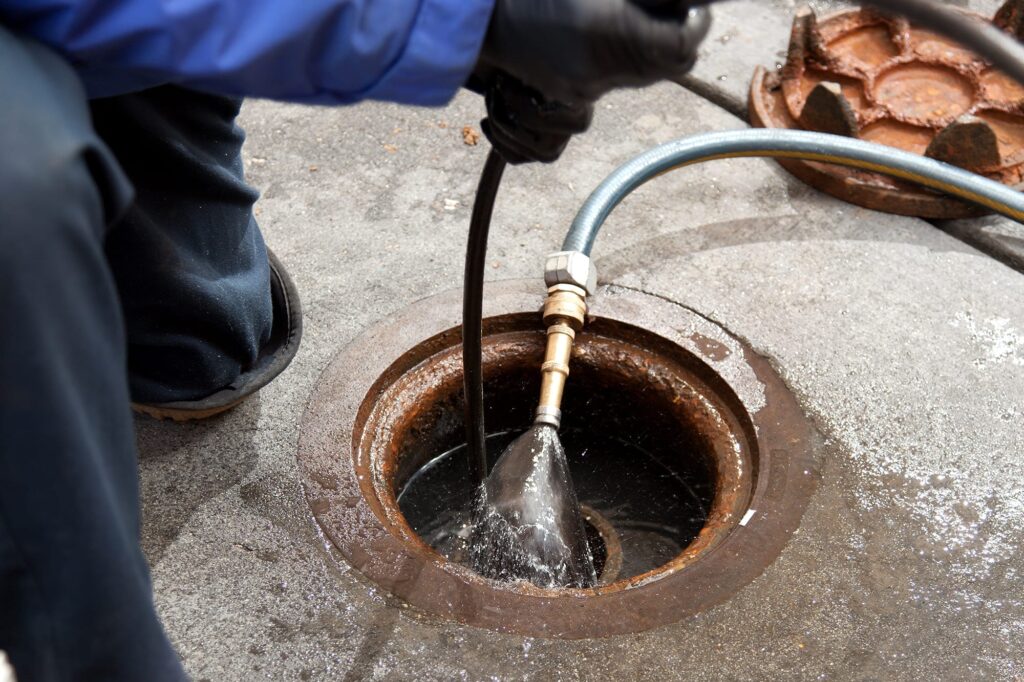 Plumber hydro jetting a sewer line through a manhole in Atlanta